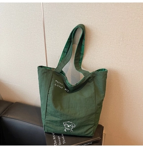 Detail of dark green tote bag featuring a cute dog print and plaid lining texture