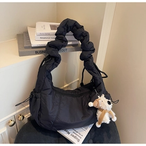 Detail of black quilted puffer bag with puffy texture and cute puppy charm accessory