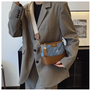 Detail of blue quilted denim bucket bag with brown leather trim and woven strap