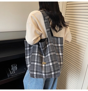 Detail of grey checkered canvas tote bag with a brown leather handmade patch