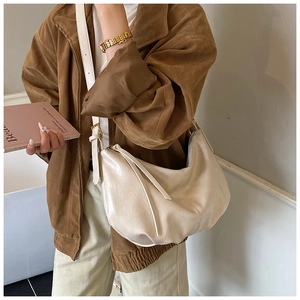 Close-up of cream soft leather hobo bag with zipper detail on a casual street outfit