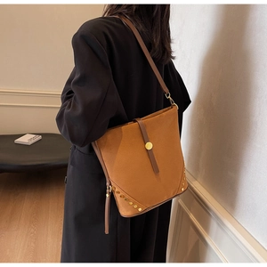 Detail view of brown suede bucket bag with gold studs and adjustable shoulder strap