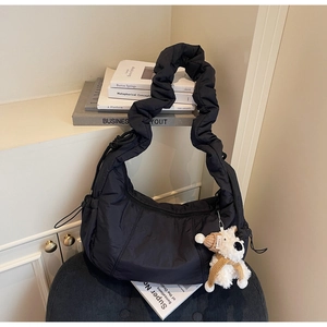Detail of black quilted puffer canvas bag featuring a cute puppy charm and ruffles