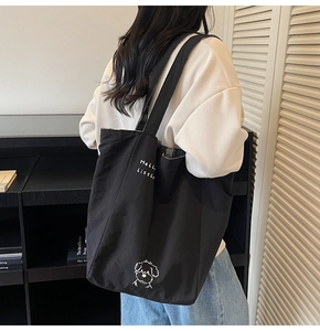 Detailed view of black canvas tote bag showing the interior black and white plaid lining