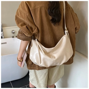 Detail of off-white crescent crossbody bag with soft faux leather texture and long zipper