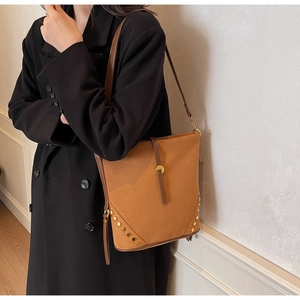 Detail view of brown suede tote bag with leather straps and gold metal rivets