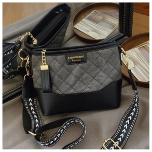 Detail of grey quilted fabric and black leather bucket bag with geometric strap