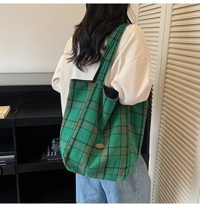 Close-up of green and black checkered tote bag with elegant oval metal logo plaque