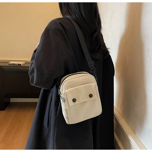 Dettaglio della borsa a tracolla minimalista in tela beige con cinturino nero regolabile