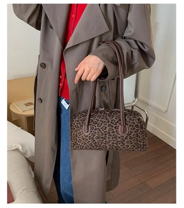 Detailed view of a vintage leopard print baguette bag with brown handles on a model