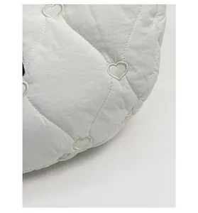 Close-up of white quilted fabric with delicate heart embroidery and durable texture