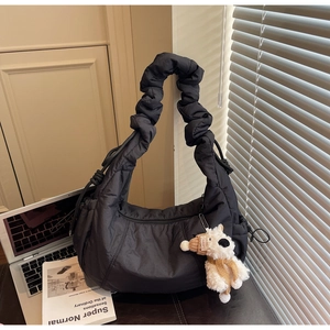 Detail of black quilted cloud bag featuring ruffled strap and cute plush dog pendant charm