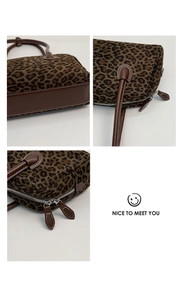Detail of vintage leopard print baguette bag featuring brown leather trim and dual metal zippers