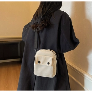 Vista posteriore di una modella con borsa a tracolla in tela crema e cinturino nero