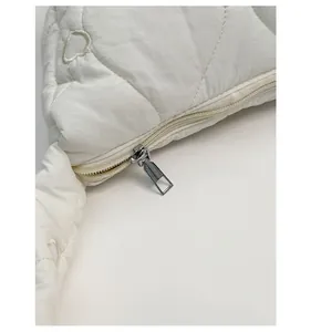 Detail of silver zipper and white heart-quilted fabric on oversized puffer dumpling bag