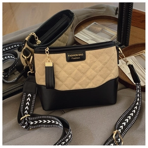 Close-up of beige quilted fabric and black leather bucket bag with fashion label