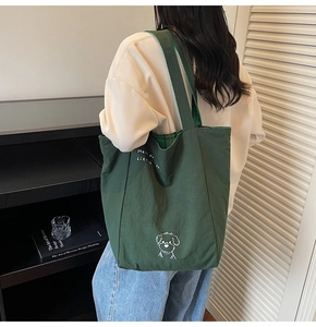 Detail of dark green canvas tote bag featuring white puppy embroidery and stylish script