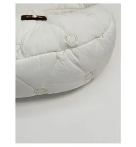 Detail of white quilted dumpling bag with heart embroidery and pearl leather tag
