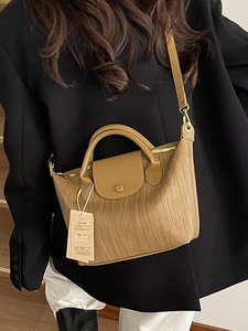 Borsa marrone con trama intrecciata, manico e tracolla indossata da una modella