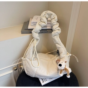 Detail of off-white quilted dumpling bag with scrunched strap and plush puppy charm