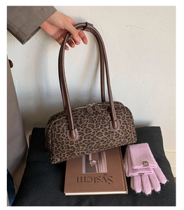 Detailed close-up of leopard print baguette bag with brown handles and dual zipper closure