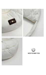 Detail of white quilted heart pattern nylon bag with pearl accents and zipper