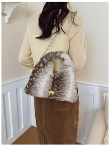 Sac bandoulière en fausse fourrure tachetée marron et blanc porté par un modèle