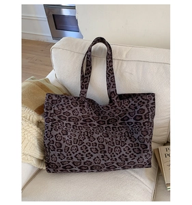 Détail d'un grand sac cabas léopard en toile marron posé sur un canapé blanc