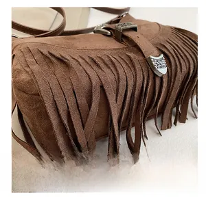 Dettaglio della borsa in pelle scamosciata marrone con frange e fibbia incisa