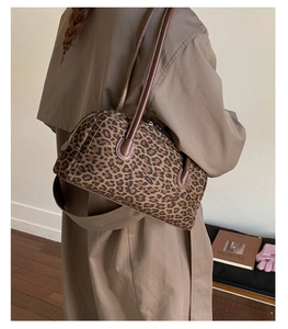 Close-up of leopard print baguette bag with brown leather strap worn on the shoulder