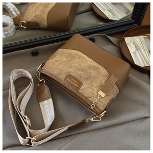 Detailed shot of quilted suede and brown leather bucket bag with metallic chain accents