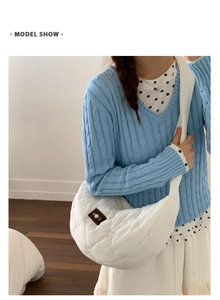 Detail showing white heart-quilted dumpling bag with pearl charm and leather label accent
