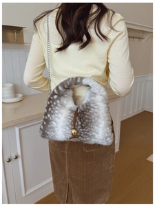 Gros plan du sac en peluche à pois gris avec un pendentif boule dorée élégant