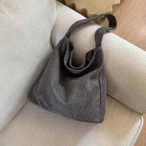 Détail du grand sac cabas gris texturé léopard posé sur un canapé en tissu crème