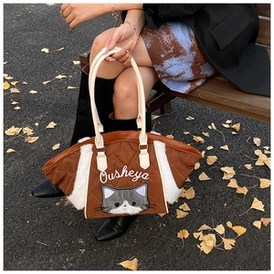 Dettaglio di una borsa tote trapuntata marrone con bordo in peluche e gatto ricamato