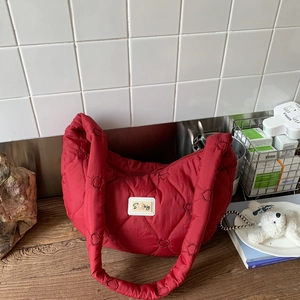 Detail of red quilted moon bag featuring heart-shaped patterns and a pearl logo plaque