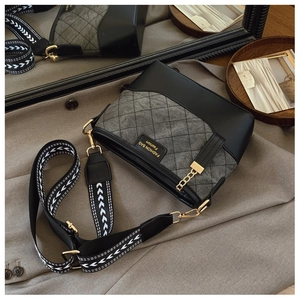 Detail of quilted bucket bag with wide jacquard strap and polished gold hardware