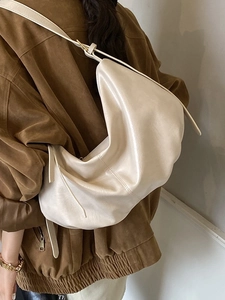 Beige large crescent hobo bag in soft faux leather with visible stitching and wide strap