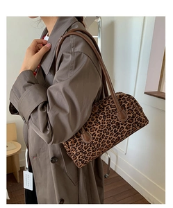 Detail of leopard print cylinder bag featuring dark brown leather handles and autumn style