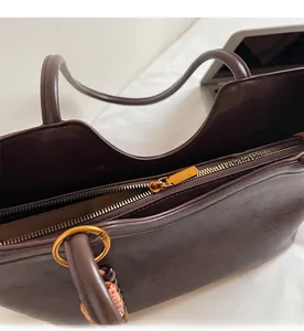 Détail d'une fermeture éclair en métal doré et texture de cuir marron foncé du sac