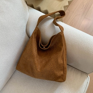 Détail du sac cabas imprimé léopard avec fermoir aimanté sur un canapé doux