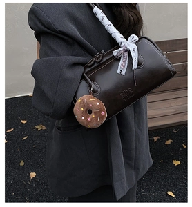 Détail du sac baguette marron avec poignée tissée et pendentif donut en peluche
