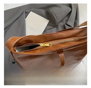 Gros plan sur la fermeture dorée et les coutures précises du sac fourre-tout brun