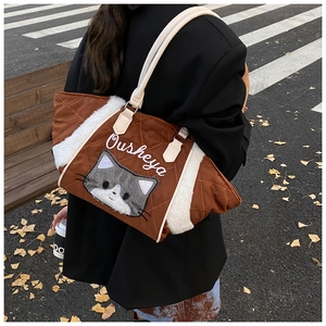 Dettaglio di una borsa tote trapuntata marrone con finiture in peluche bianco e ricamo a gatto