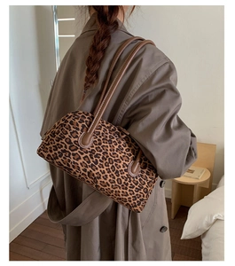Detail of vintage leopard print baguette bag with brown leather handles and white stitching