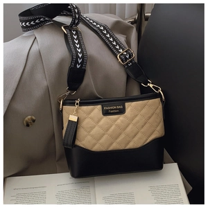Detail of quilted bucket bag with geometric strap and khaki contrast over a book