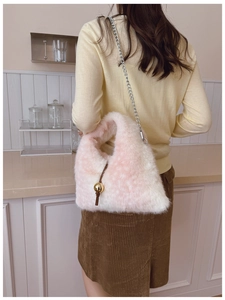 Détail d'un sac bandoulière en peluche rose et blanc avec chaîne sur l'épaule