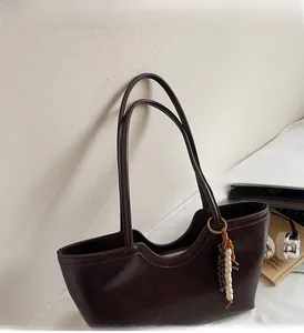 Détail du grand sac cabas marron foncé avec breloque perlée à côté d'un ordinateur