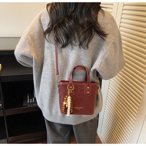 Detail of burgundy leopard embossed bucket bag with wooden beads and gold logo