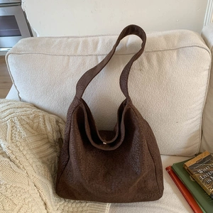 Détail d'un sac hobo marron foncé à imprimé léopard avec texture sur un canapé